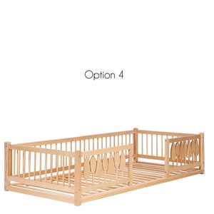 Puede incluir: Una cama de madera para ni&ntilde;os peque&ntilde;os con una barandilla de seguridad en un lado y una barandilla decorativa con forma de hoja en el otro lado. La cama est&aacute; hecha de madera natural y tiene una base de listones.