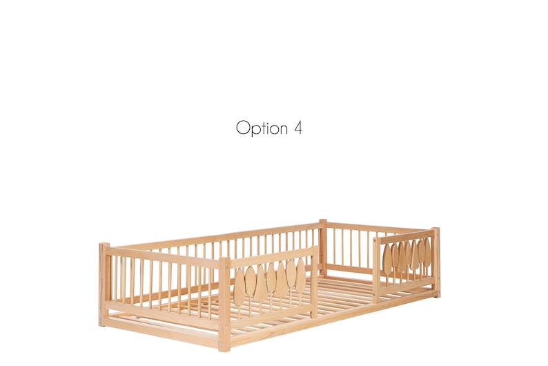 Puede incluir: Una cama de madera para ni&ntilde;os peque&ntilde;os con una barandilla de seguridad en un lado y una barandilla decorativa con forma de hoja en el otro lado. La cama est&aacute; hecha de madera natural y tiene una base de listones.