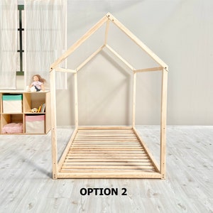 May include: A wooden bed frame in the shape of a house. The frame is made of natural wood and has a slatted base. The frame is labeled "OPTION 2".