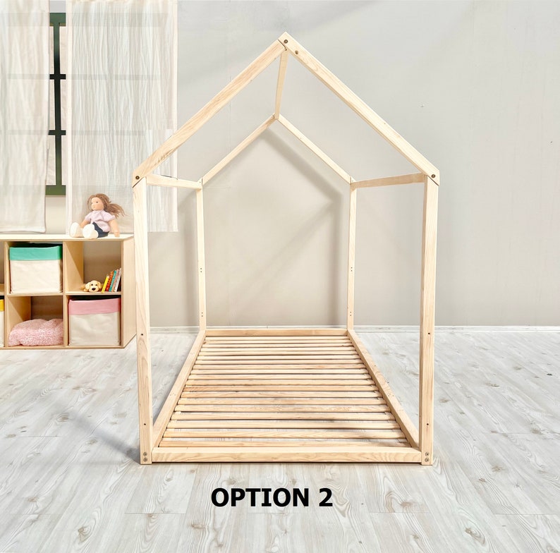 May include: A wooden bed frame in the shape of a house. The frame is made of natural wood and has a slatted base. The frame is labeled "OPTION 2".