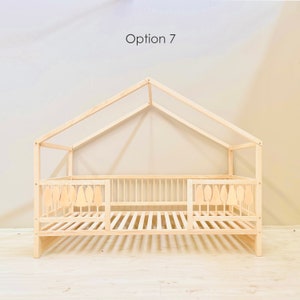 May include: A wooden toddler bed with a house-shaped frame and a slatted mattress. The bed has two side rails with decorative cutouts shaped like trees. The text "Option 7" is visible at the top of the image.