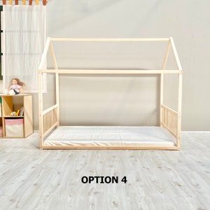May include: A wooden bed frame in the shape of a house with a white mattress. The bed frame is made of natural wood and has a simple design. The bed is sitting on a light wood floor. The text "OPTION 4" is printed below the bed.
