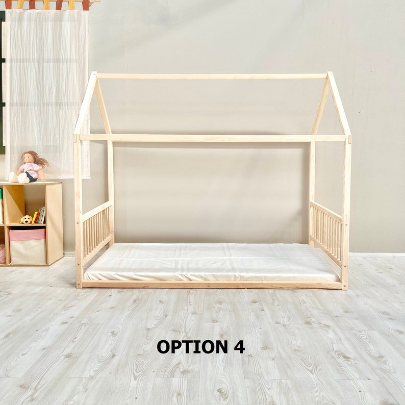 May include: A wooden bed frame in the shape of a house with a white mattress. The bed frame is made of natural wood and has a simple design. The bed is sitting on a light wood floor. The text "OPTION 4" is printed below the bed.