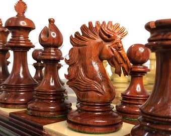 Puede incluir: Un juego de ajedrez de madera con piezas talladas de forma intrincada. El juego incluye un caballo, una torre, un alfil y un peón. Las piezas están hechas de una madera rica, de color marrón rojizo.