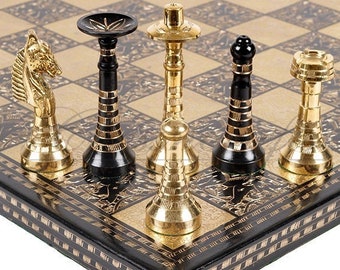 Può includere: Un set di scacchi nero e oro con dettagli decorativi sulla scacchiera. I pezzi sono in metallo e hanno un design tradizionale.