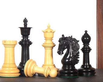 Op de afbeelding: Een verzameling schaakstukken, waaronder een toren, een koning, een dame, een paard en een loper. De stukken zijn zwart en crèmekleurig, waarbij de dame op haar zij ligt. De stukken zijn op een donkere ondergrond geplaatst.