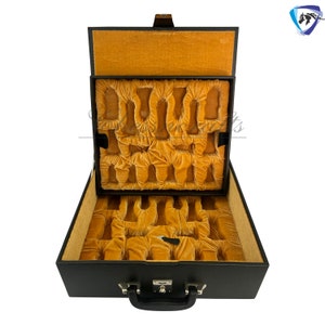 May include: Black leather case with a gold velvet interior. The case has a handle and a lock. It is designed to hold multiple items, such as watches or jewelry.