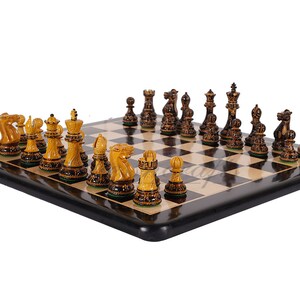 Pu&ograve; includere: Un set di scacchi in legno con pezzi neri e dorati su una scacchiera bianca e nera. I pezzi sono finemente intagliati e hanno un design tradizionale.