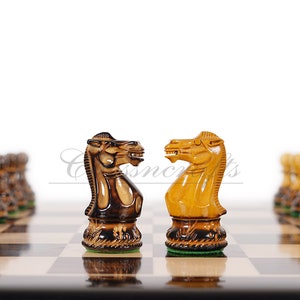Pu&ograve; includere: Due cavalieri degli scacchi in legno si fronteggiano su una scacchiera. Il cavaliere a sinistra &egrave; marrone scuro e il cavaliere a destra &egrave; marrone chiaro. La scacchiera &egrave; in legno con caselle chiare e scure alternate.