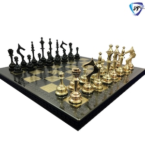 Peut inclure: Un jeu d'échecs noir et or avec un échiquier noir et blanc. Les pièces d'échecs sont en métal et ont un design traditionnel.
