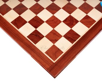 May include: Close-up of the corner of a wooden chessboard with a red mahogany finish. The board has a light wood and dark wood checkerboard pattern. The board is made of high-quality wood and has a smooth, polished finish.