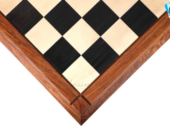 May include: A square wooden chessboard featuring a high-contrast pattern of alternating light cream and dark black squares. The board is framed by a thick, polished reddish-brown wooden border with visible grain patterns and mitered corners.