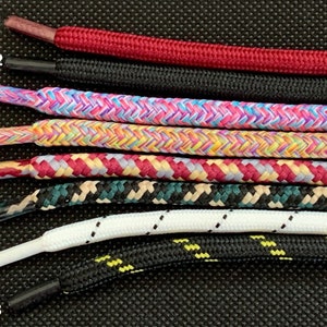 K&ouml;nnte beinhalten: Acht verschiedene Schn&uuml;rsenkel-Stile, nummeriert von 1 bis 8, werden vor einem schwarzen Hintergrund angezeigt. Die Schn&uuml;rsenkel sind in verschiedenen Farben und Mustern, darunter Rot, Schwarz, Pink, Gelb, Blau, Gr&uuml;n, Wei&szlig; und Beige.