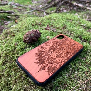 K&ouml;nnte beinhalten: Eine Handyh&uuml;lle aus Holz mit einem detailliert lasergravierten Design eines L&ouml;wenkopfes. Die H&uuml;lle ist rotbraun und hat einen schwarzen Rand.