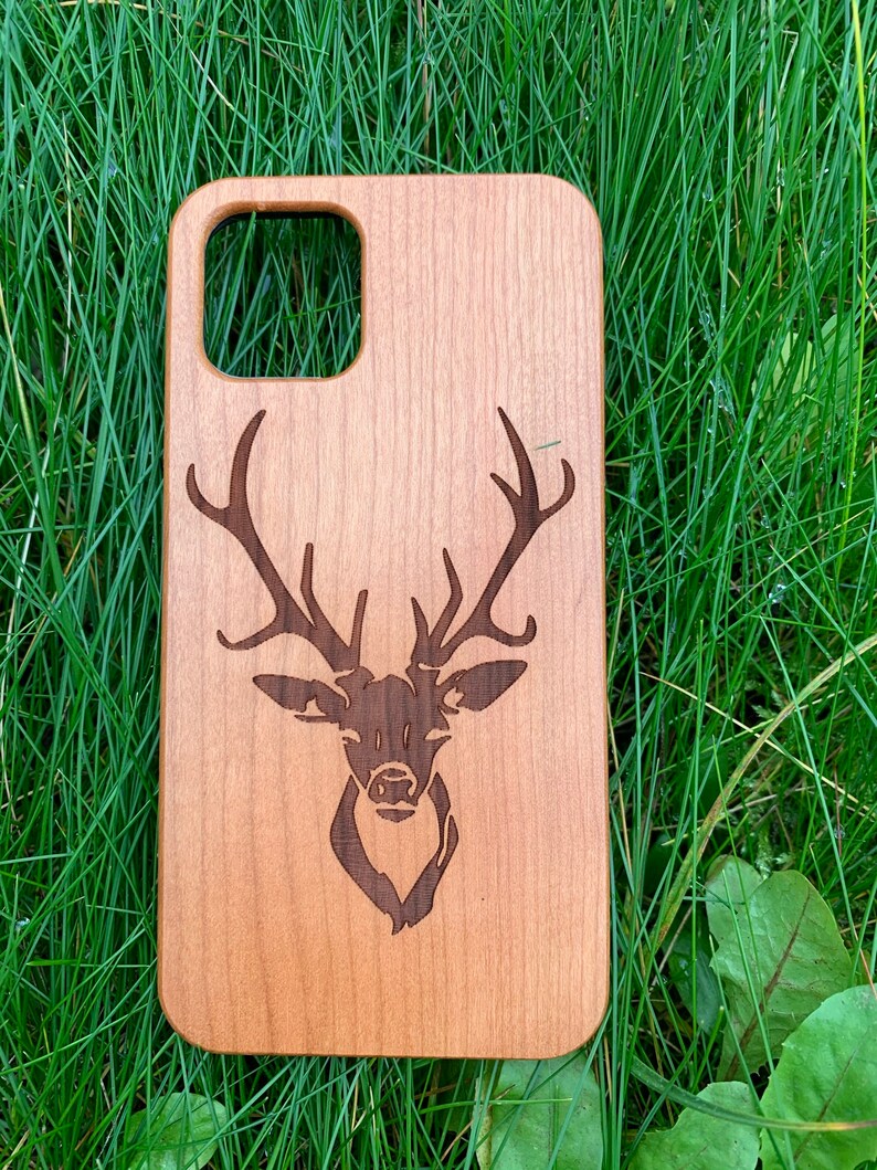 May include: A wooden phone case with a laser-engraved deer head design. The case is a light brown color and has a natural wood grain.