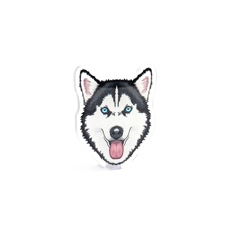 May include: A sticker featuring a cartoon husky dog with blue eyes and a pink tongue sticking out. The dog has black and white fur.