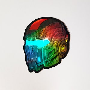 Pode incluir: Um autocolante hologr&aacute;fico de um capacete futurista com viseira. O capacete apresenta um gradiente de cores vermelho, laranja, amarelo, verde e azul. A viseira brilha com uma luz azul brilhante. O design tem uma est&eacute;tica mec&acirc;nica detalhada.