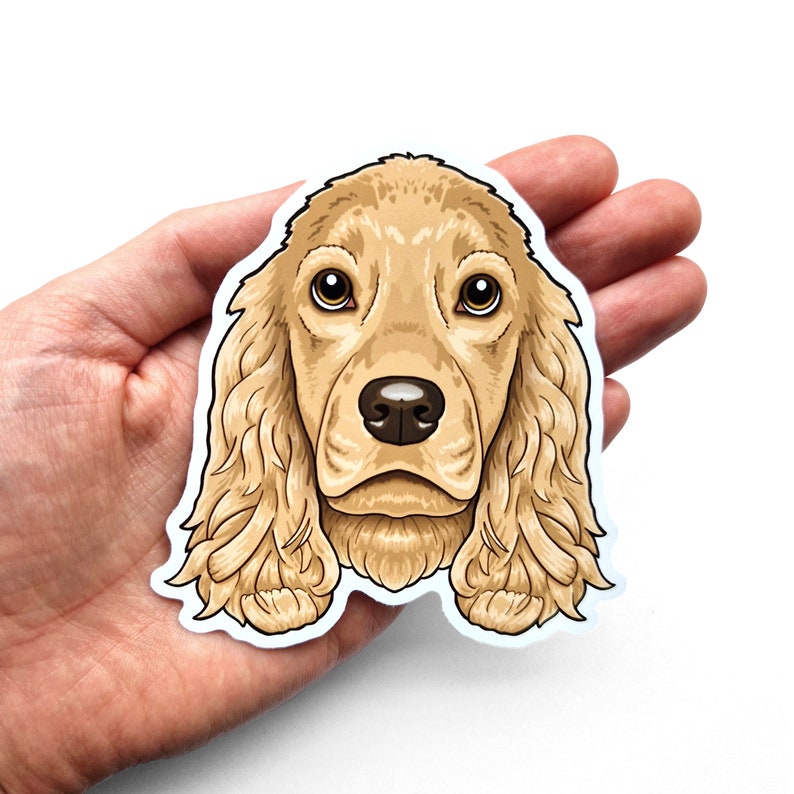 Puede incluir: Una pegatina con una ilustraci&oacute;n de dibujos animados de la cabeza de un perro cocker spaniel dorado. El perro tiene ojos marrones y una nariz marr&oacute;n claro.