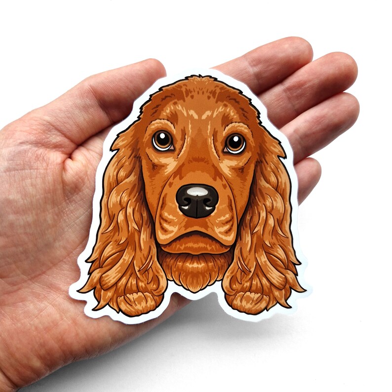 Puede incluir: Una pegatina con una ilustraci&oacute;n de dibujos animados de un perro Cocker Spaniel marr&oacute;n y blanco sobre un fondo blanco.