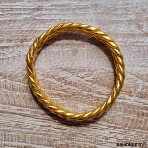 May include: A gold-colored bangle bracelet with a twisted rope design.