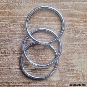 May include: Three silver metal rings stacked on top of each other. The rings are smooth and shiny.