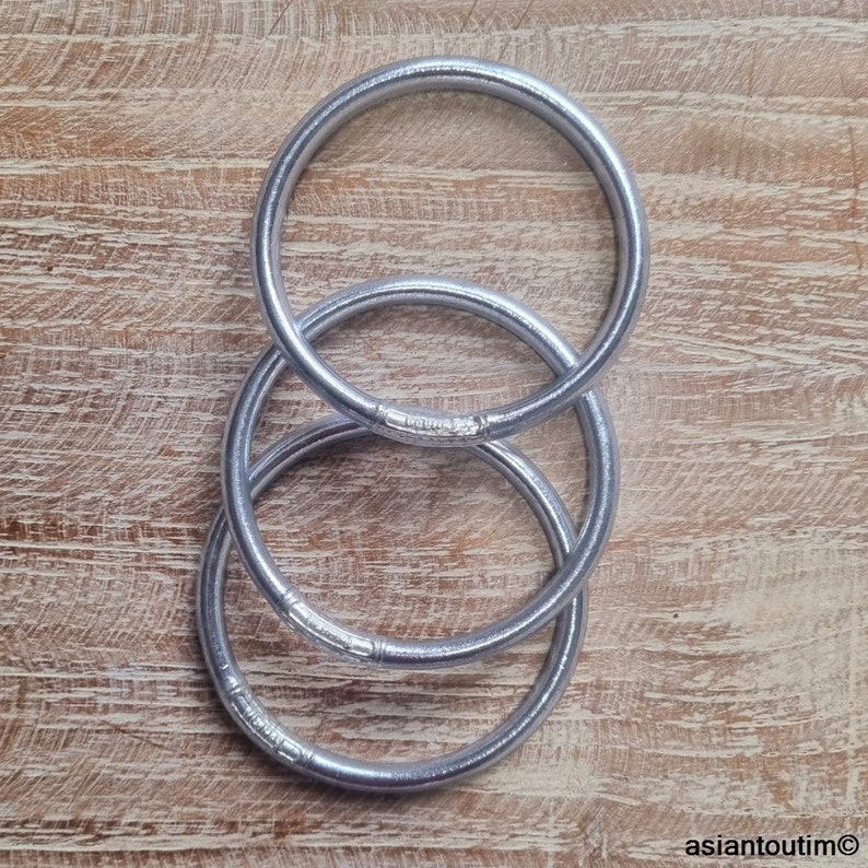 May include: Three silver metal rings stacked on top of each other. The rings are smooth and shiny.