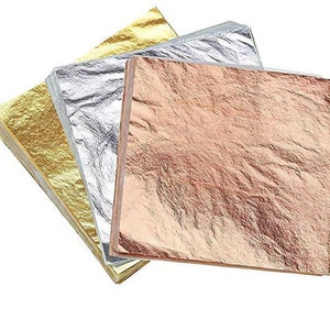 May include: A stack of gold, silver, and rose gold leaf sheets. The sheets are thin and delicate, and they are perfect for adding a touch of elegance to any project.