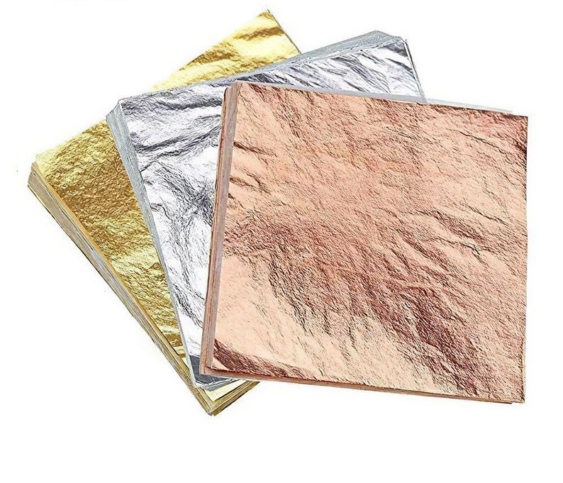May include: A stack of gold, silver, and rose gold leaf sheets. The sheets are thin and delicate, and they are perfect for adding a touch of elegance to any project.
