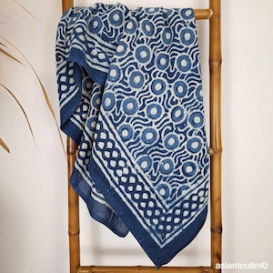 Peut inclure: Textile à motifs bleu et blanc drapé sur une échelle en bambou. Le tissu présente un motif répétitif de cercles et de lignes ondulées, avec une bordure de formes interconnectées. La palette de couleurs est principalement indigo et blanc.