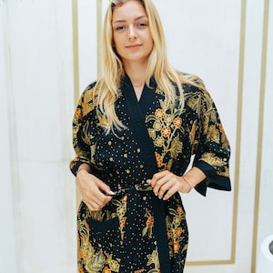 May include: A black silk robe with a floral pattern in gold and orange. The robe has a tie belt and long sleeves.