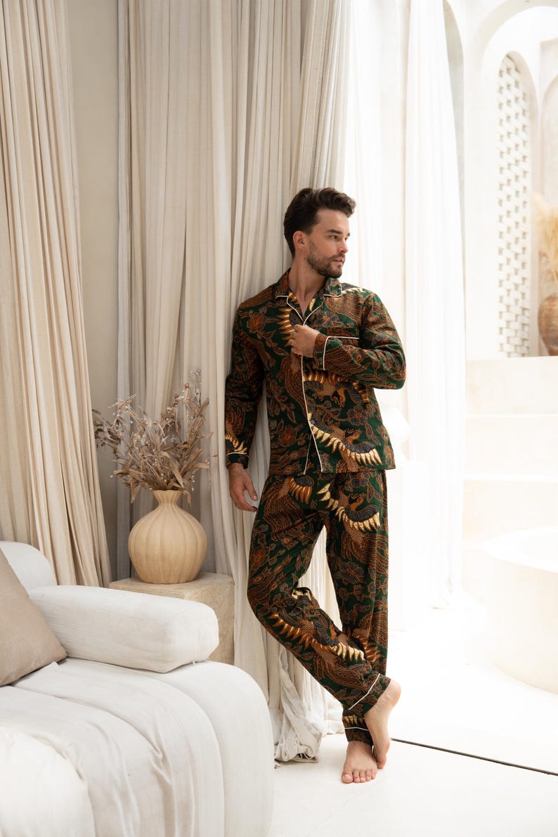 Puede incluir: Conjunto de pijama con estampado verde y marr&oacute;n con ribete blanco. La parte superior de manga larga y los pantalones presentan un dise&ntilde;o repetitivo. El pijama est&aacute; hecho de un material suave. El modelo est&aacute; cerca de una ventana.