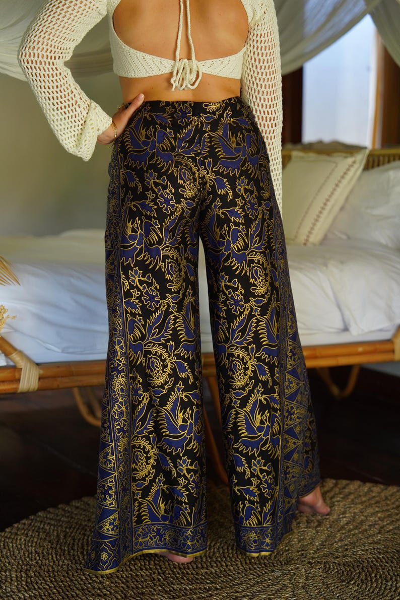 May include: Black wide-leg pants with a blue and gold floral pattern. The pants have a high waist and a loose fit.
