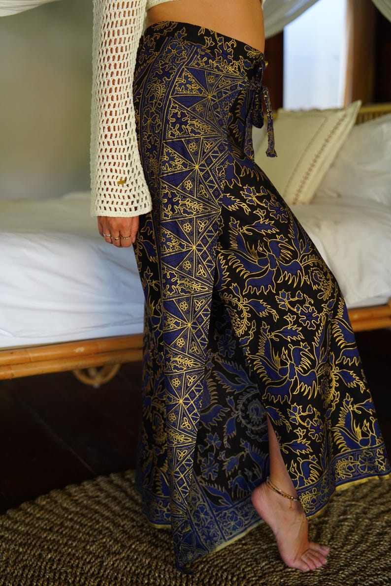 May include: A long, flowing skirt with a black background and a blue and gold patterned design. The skirt has a side slit and a tie at the waist.