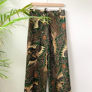 May include: Green wide-leg pants with a gold and brown floral print featuring a bird design.