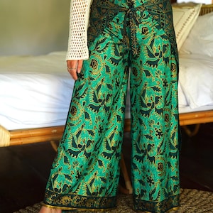 Peut inclure: Pantalon large vert à motif floral et accents dorés. Le pantalon a un lien à la taille et une fente sur le côté.