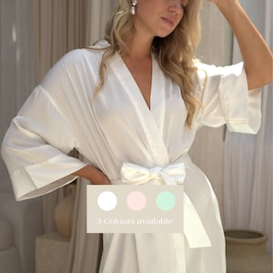 May include: White satin robe with a tie sash. The robe has 3/4 sleeves and a relaxed fit. 3 Colours available: white, pink, and mint.