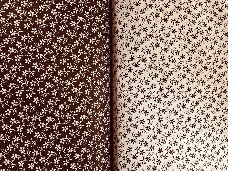 May include: Two pieces of fabric displayed side by side. The left piece is dark brown with a repeating pattern of small white flowers and curved lines. The right piece is cream-colored with a repeating pattern of small dark brown flowers.