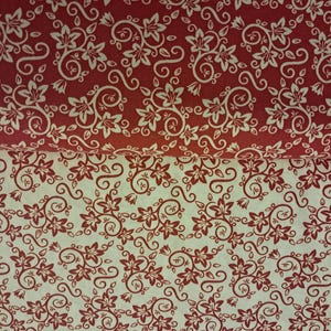 May include: Two folded layers of fabric featuring a repeating floral vine pattern. The top layer is deep red with white floral motifs, while the bottom layer is off-white with deep red floral motifs, both displaying identical swirling leaf designs.