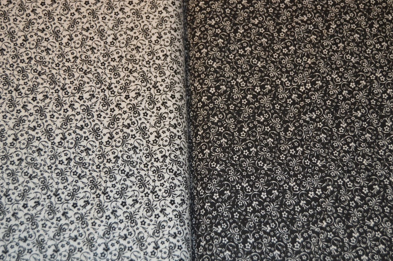 May include: A fabric featuring a dense, repeating pattern of small flowers and swirling vine motifs. The left side displays a white background with black print, while the right side shows a black background with white print, creating a high contrast.
