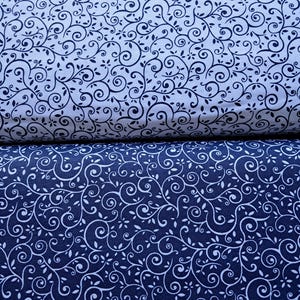 May include: Two folded pieces of fabric featuring a continuous scrolling vine and leaf pattern. The top fabric is white with dark navy blue lines, while the bottom fabric is dark navy blue with white lines, creating a contrasting color scheme.