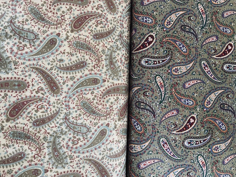 May include: Two pieces of fabric featuring a dense paisley pattern. The left side displays a cream background with muted green, brown, and blue paisley motifs. The right side shows an olive green background with dark brown, blue, and white paisley designs.