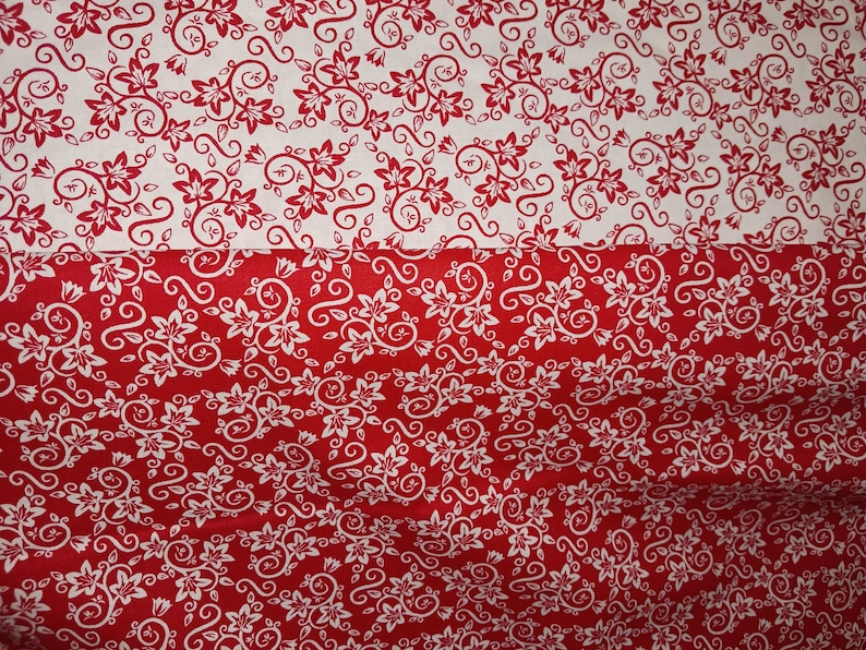 May include: A fabric featuring a two-tone floral pattern with a horizontal split. The top section displays red floral and vine motifs on a white background, while the bottom section reverses the color scheme with white floral motifs on a red background.