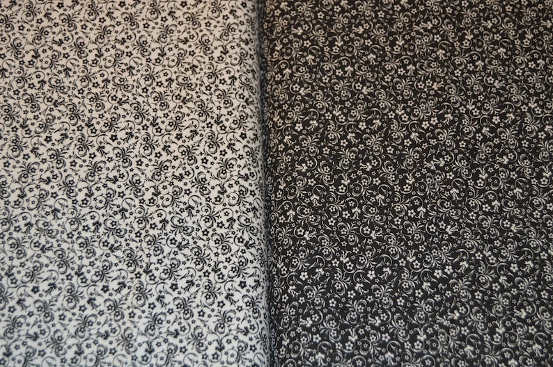 May include: A fabric featuring a dense, repeating pattern of small flowers and swirling vine motifs. The left side displays a white background with black print, while the right side shows a black background with white print, creating a high contrast.