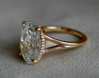 May include: A gold engagement ring with a large oval-shaped diamond set in a halo of smaller diamonds. The ring has a split shank design.