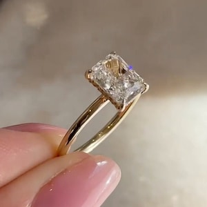 Puede incluir: Un anillo de oro con un diamante de forma cuadrada engastado en garras.