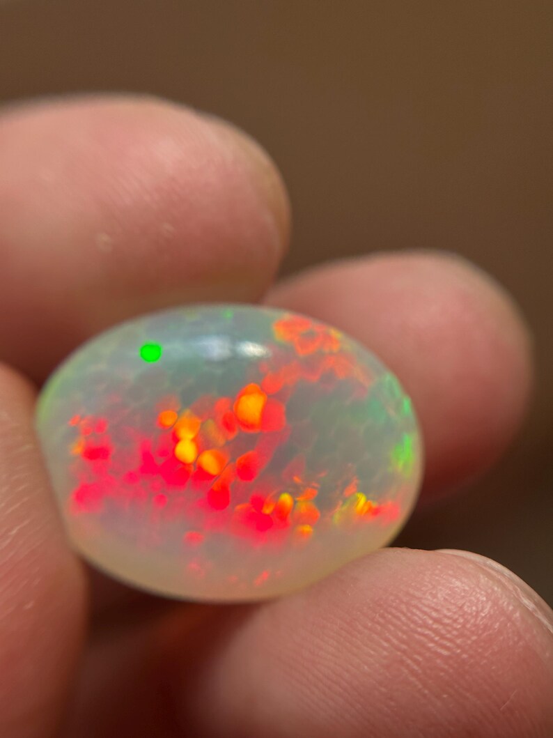 Rare 13-carat oval honeycomb opal loose gemstone with intense multi-color fire.