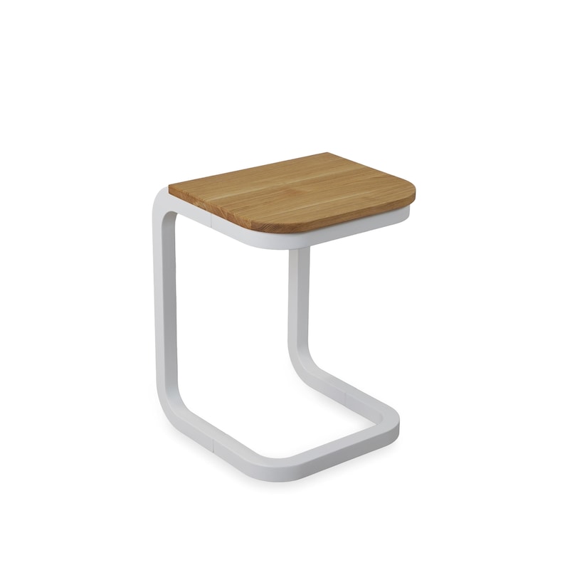 Op de afbeelding: Een moderne bijzettafel met een wit metalen frame en een natuurhouten blad. De tafel heeft een uniek C-vormig ontwerp, met een rechthoekig tafelblad en een enkele poot die de basis vormt. Het tafelblad meet ongeveer 38 cm bij 30 cm.