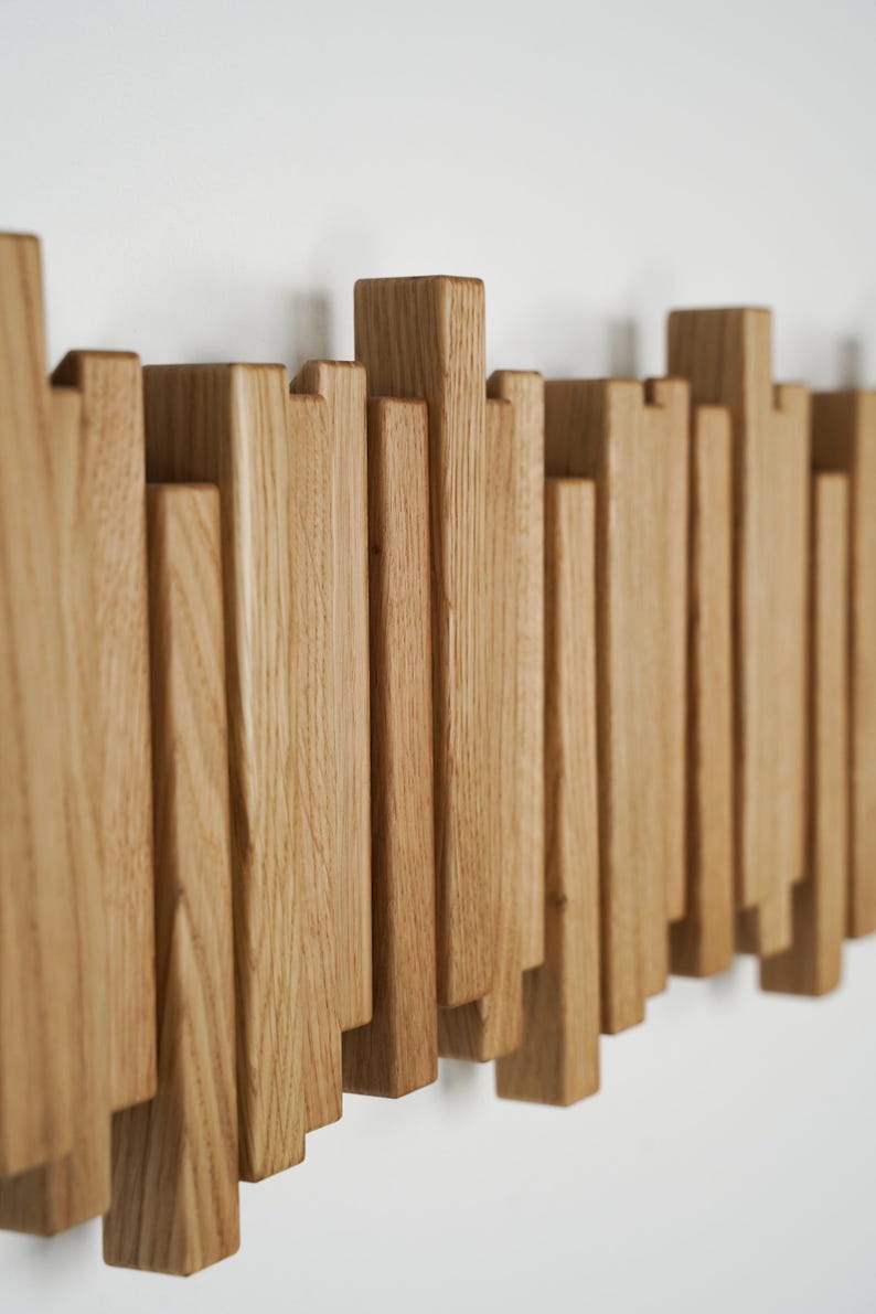 May include: A wooden wall art piece featuring a series of vertical, rectangular wooden blocks of varying heights. The blocks are arranged in a staggered pattern, creating a textured, three-dimensional effect. The wood has a natural, light brown color.