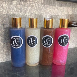 May include: Four bottles of body scrub with gold lids and labels that say "Love & Jude". The bottles are blue, white, brown, and pink.