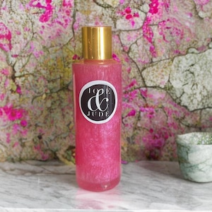 May include: A pink bottle with a gold lid and a black and white label that says "Love & Jude". The bottle is filled with a pink liquid with glitter.